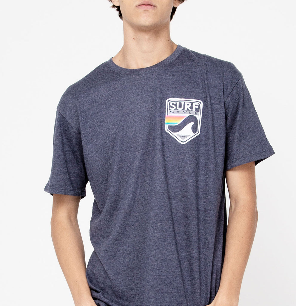 male showing the front design on the Surf Style Pastel Shield shirt on heathered blue shirt